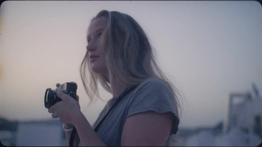 A woman takes a photograph with a camera at sunset