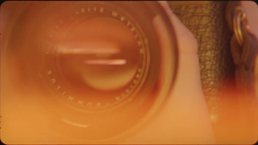 A hand turns a lens on a camera to zoom in and out