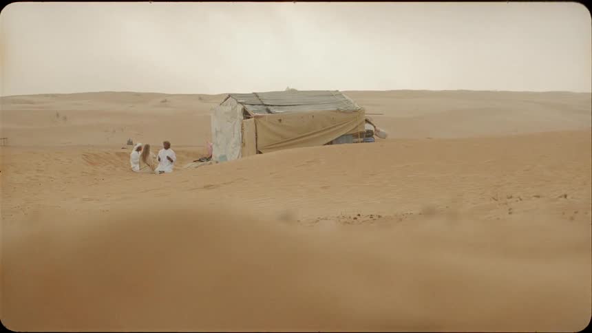 People sit by the tent in the desert