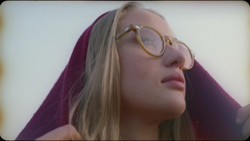 A blond haired woman puts a red sheet on her head