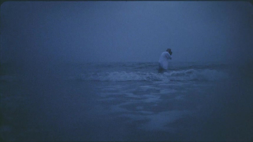 An arab man stands in the ocean water and washes his face