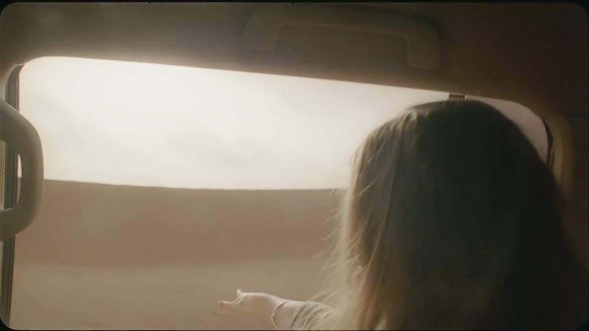 Woman riding in a vehicle and sticks her hand out the window