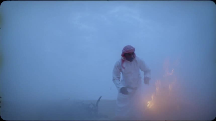 Man throws kindling on a fire outside in the desert