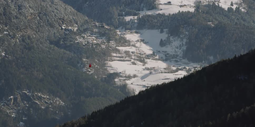 A red helicopter flies between two mountains