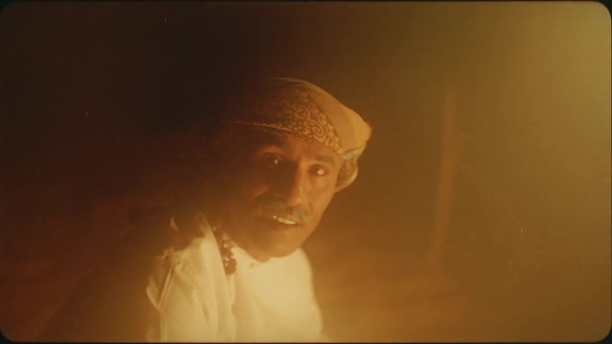 Man wearing a turban sits in the dark as he tosses something
