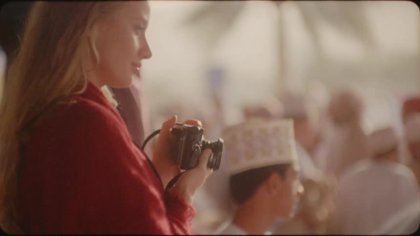 A woman photographs a gathering of arab men on a sunny day