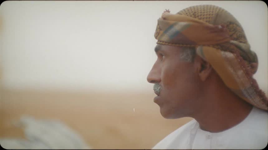 An arab man talks and gestures to someone outside