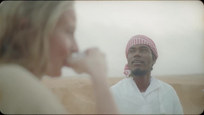A woman talks and drinks with a middle eastern man