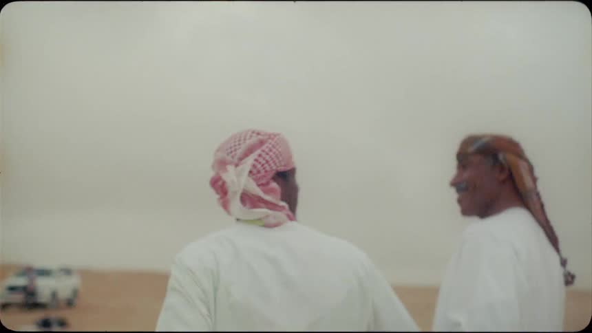 Two men walk in the desert on a cloudy day