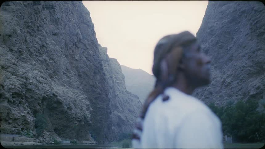 Man stands near a lake between the mountains