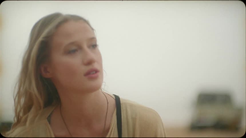 A blond haired woman stands and talks in the desert