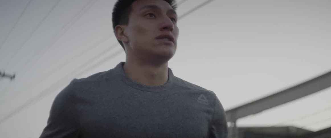 Man is jogging down a street at sunrise