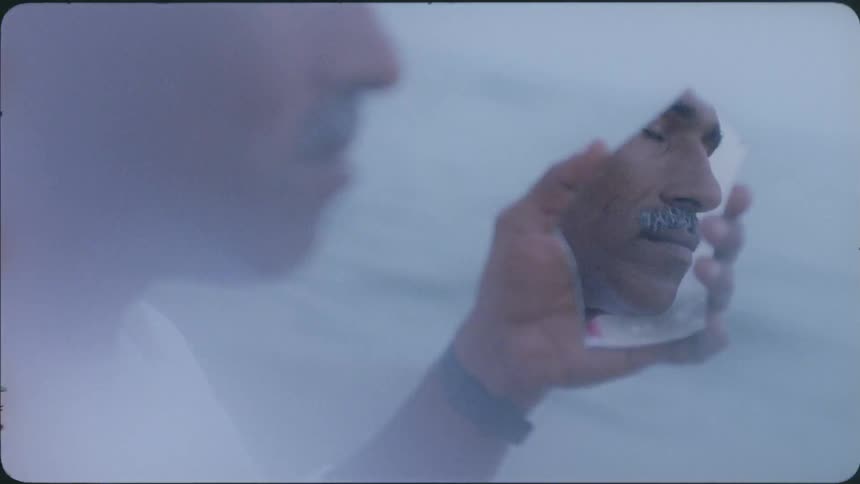 Man looks at his reflection in a small mirror