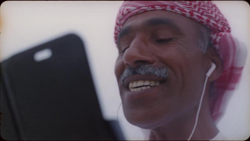 Man smiles and talks looking at a phone