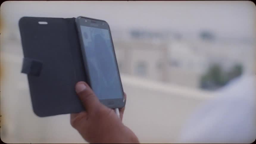A man holds his phone and has a video chat outside
