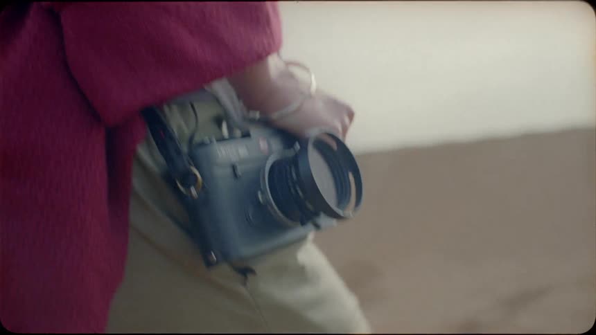 A woman walks in the desert with a camera