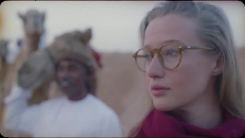 A man and woman in the desert with camels