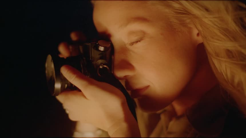 A blond haired woman takes photographs outside at night