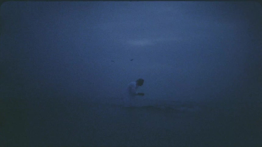 A man is washing his face in a river on a cloudy day