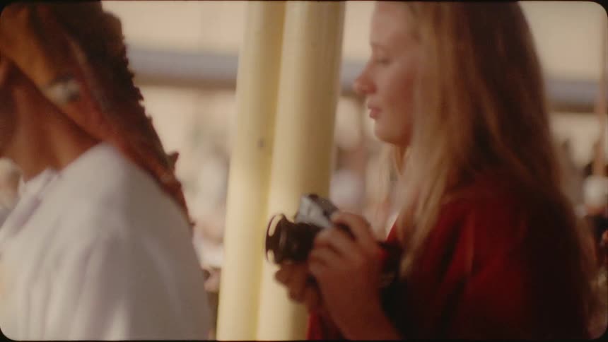 A woman is holding a camera as she visits a market with an arab man in daylight