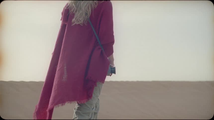 Woman wearing a red cloak walks through the desert