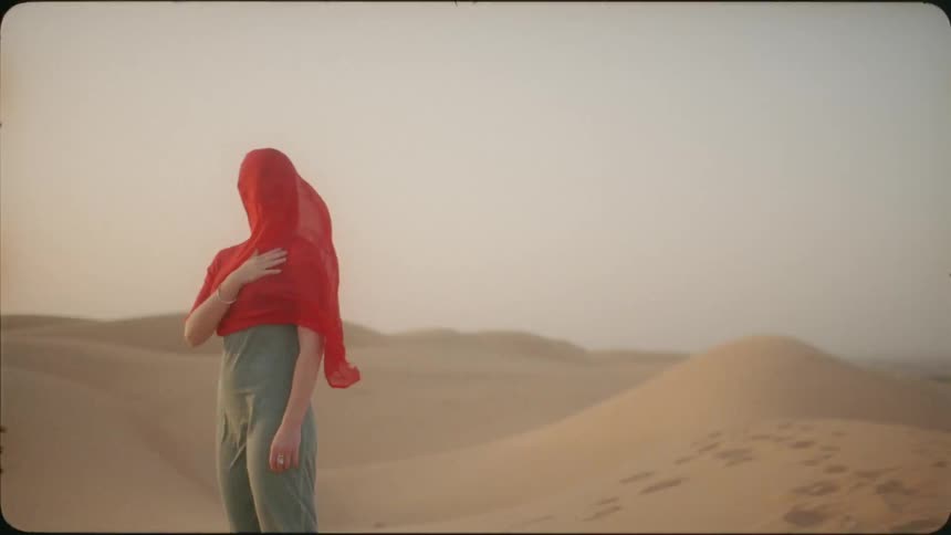 The wind blows a red scarf against a woman's face