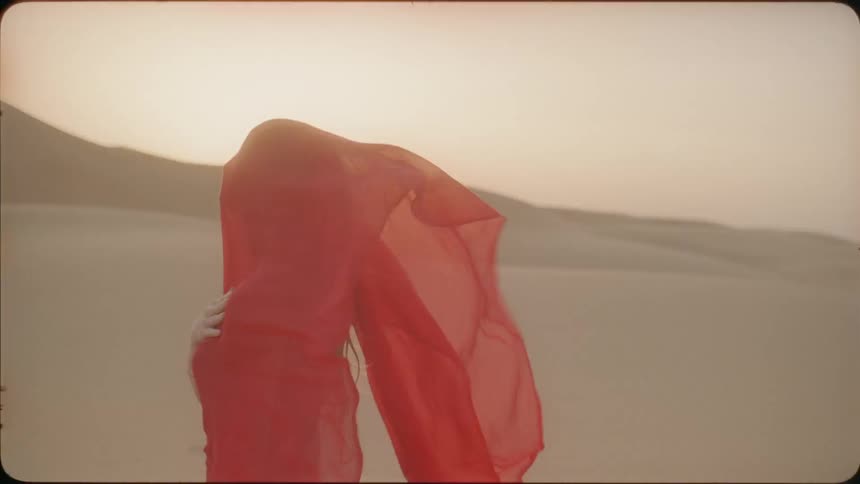 Woman wears a red veil as it blows in the breeze