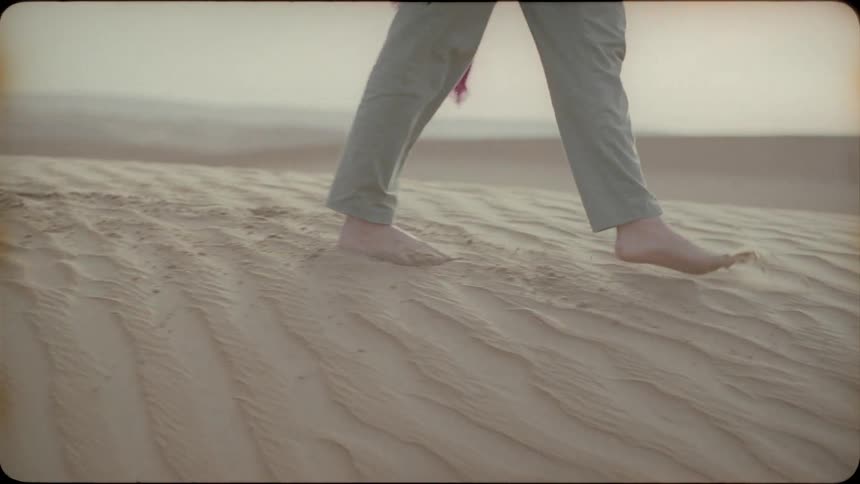 Woman kicks up the sand as she walks in the desert