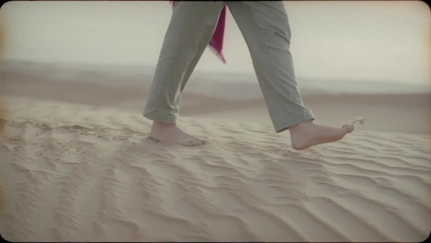 Woman drags her feet as she walks on the sand