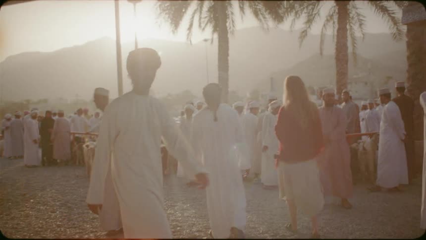 Woman walks in a village among many men