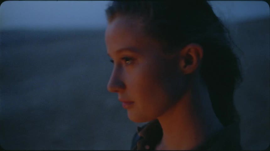 Woman stands in a desert at dusk