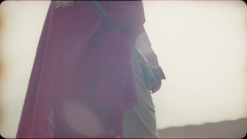 Woman walks with a camera hanging from a strap