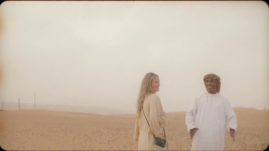 Man and woman stand in desert talking
