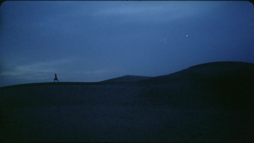 Person walks across a hilly desert at night