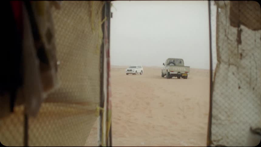 Vehicles are sitting parked in the sand in a desert during the day
