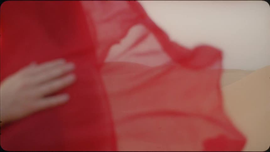A red sheet on a woman blows in the wind