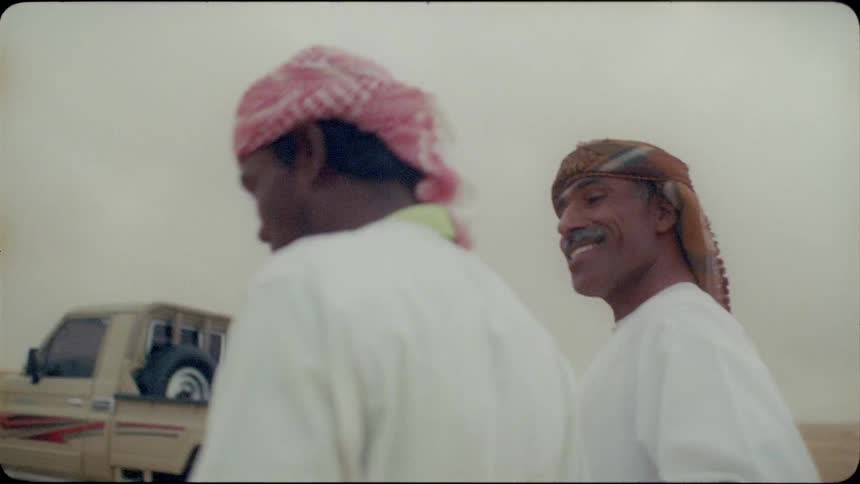 Two arab men are walking and talking in the desert on a cloudy day
