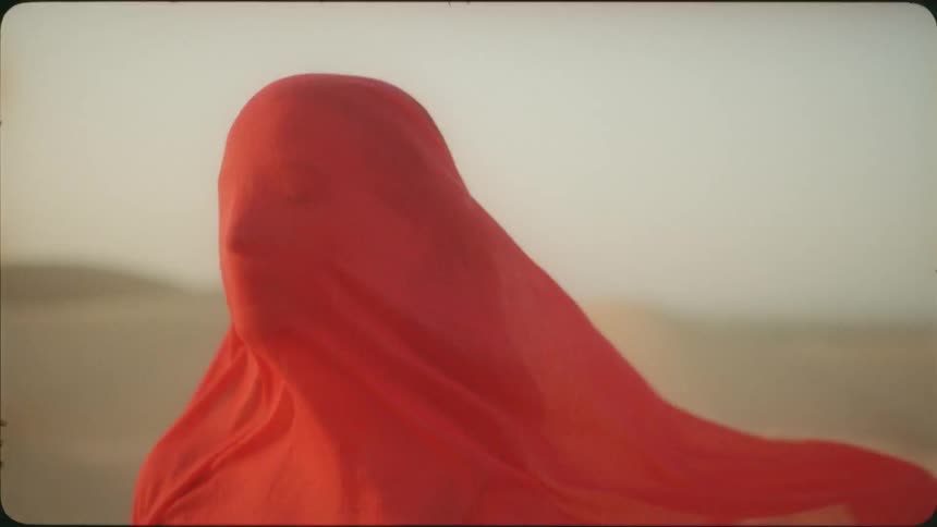 Red veil blows in the wind as it covers a woman
