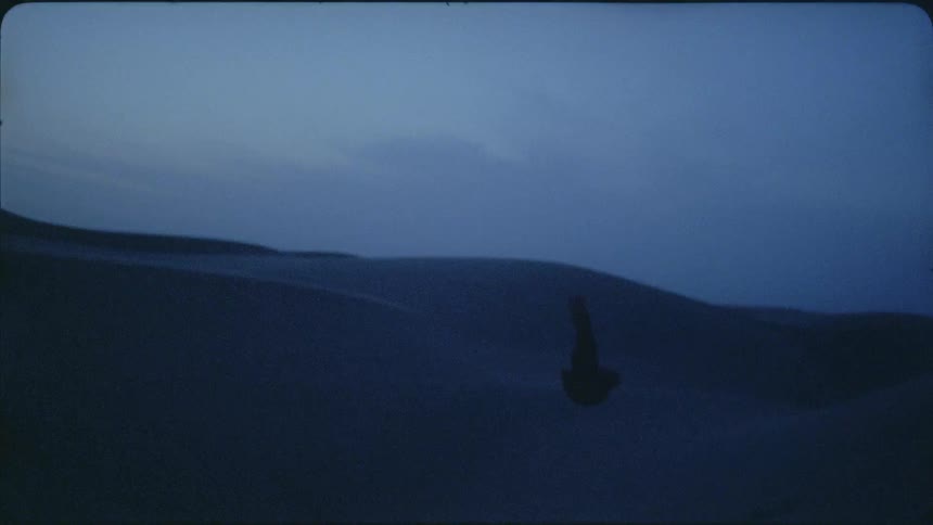 A scarf floats and falls with the breeze at dusk in a desert landscape