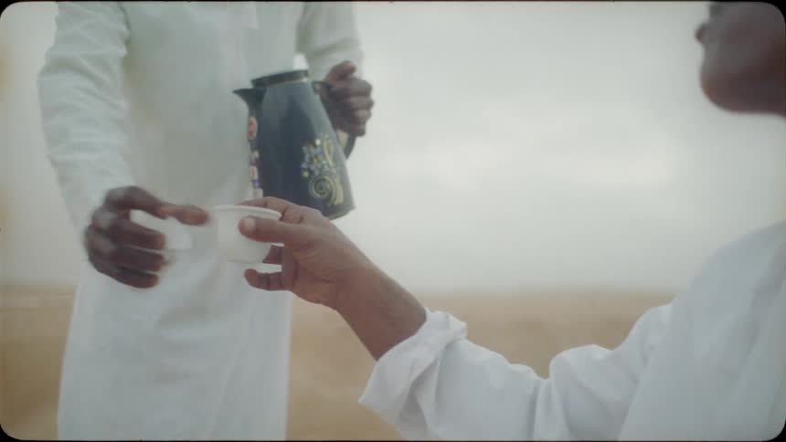 Two men are drinking and eating in the desert