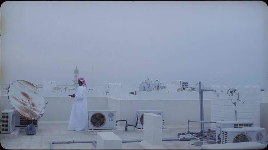 Man wearing a turban stands near a satellite dish