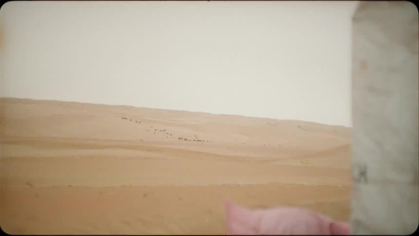 People or animals are just visible on the sand dunes