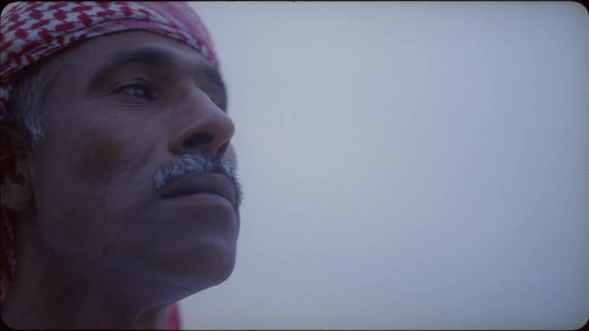 A man wearing a red and white turban is looking around