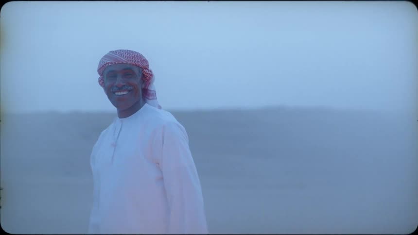A man standing in the desert smiles