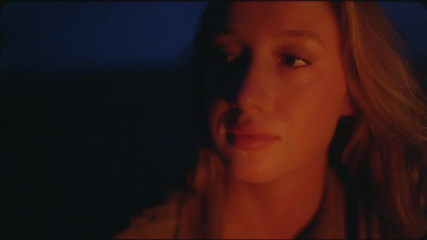 A woman talks in front of a fire at dawn