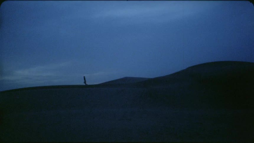 Man walks over the sand in the desert at night