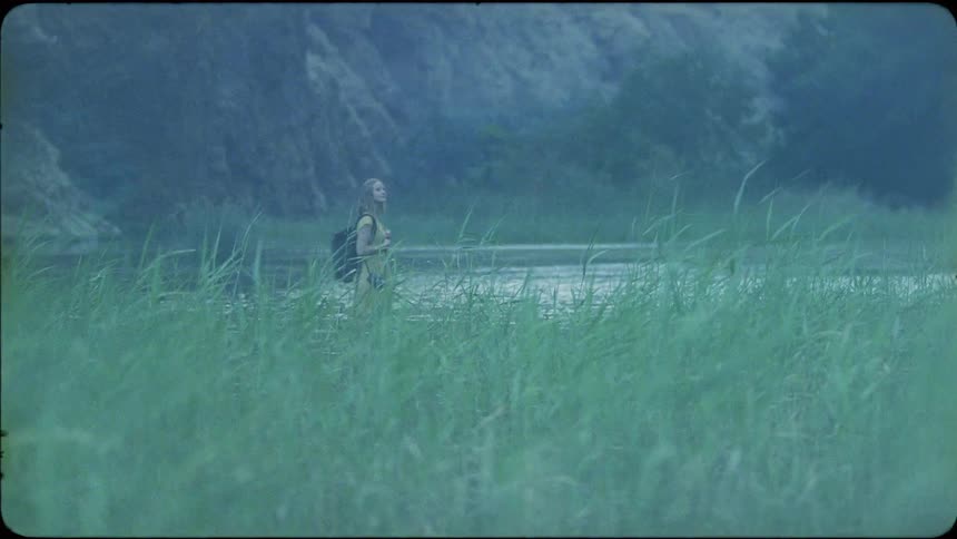 The woman is hiking past the tall grass