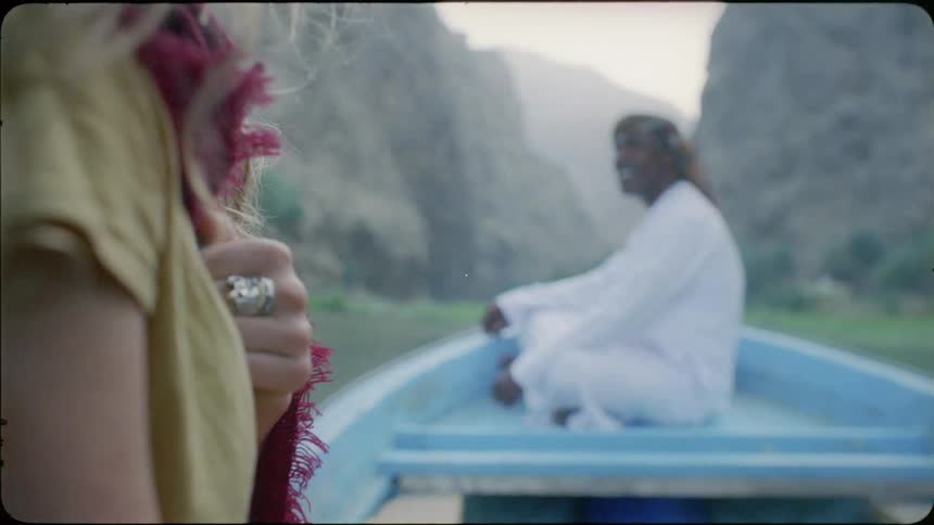 A man sits on the moving boat smiling