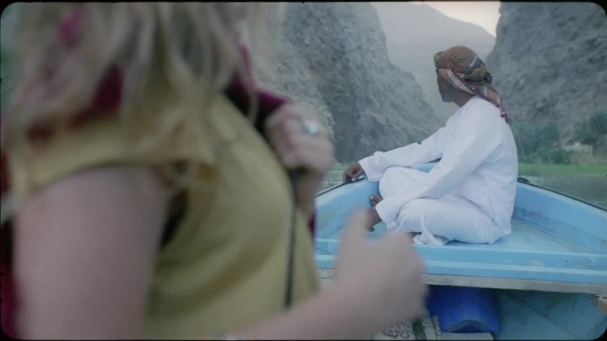 A man sitting on a boat turns and smiles at a woman
