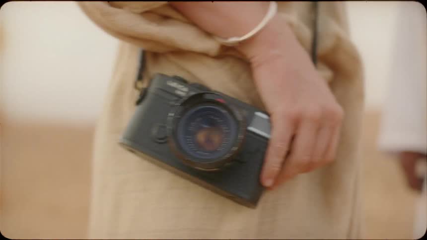 The woman is holding a camera by her side